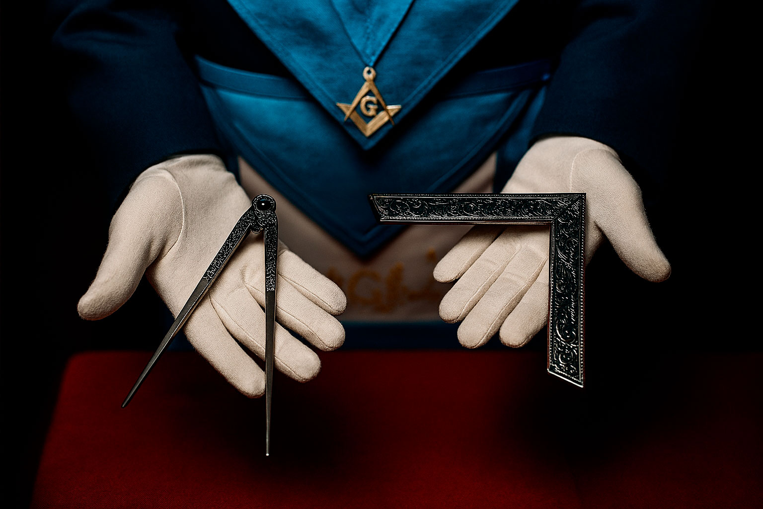 Símbolos del compás y la escuadra sostenidos por un masón en la logia masónica