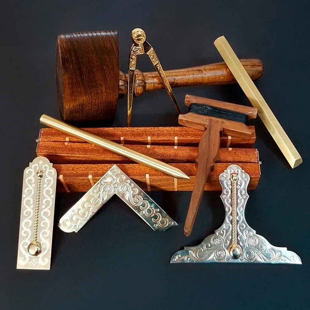 Instrumentos simbólicos de la masonería: escuadra, compás, plomada, regla, mazo y nivel sobre fondo oscuro que nos ayudan a encontrar respuestas a ¿Qué significa ser masón?
